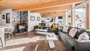 A modern living room with a fireplace, grey sofa, and wooden ceiling.