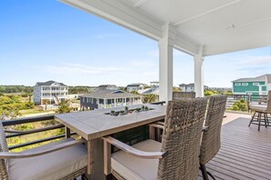 A covered outdoor patio with a table and chairs, overlooking a residential area. - 1040 Break / 1040 Ocean Blvd West 4 Bedroom Home by RedAwning (Supply)