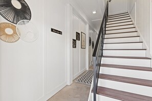 Eine Treppe mit schwarzer Handläufe führt zu einer oberen Etage, weiße Wände und ein gemustertes Teppich.