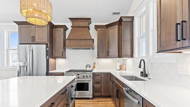 A modern kitchen with a large island, stainless steel appliances, and wooden cabinetry. - 1040 Break / 1040 Ocean Blvd West 4 Bedroom Home by RedAwning (Supply)