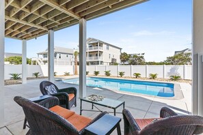 A covered outdoor area with a pool, wicker furniture, and a view of residential buildings. - 1040 Break / 1040 Ocean Blvd West 4 Bedroom Home by RedAwning (Supply)