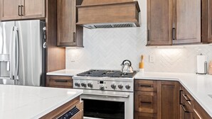 A modern kitchen with wooden cabinets, a stainless steel stove, and a built-in oven. - 1040 Break / 1040 Ocean Blvd West 4 Bedroom Home by RedAwning (Supply)