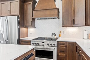Eine moderne Küche mit Holzausstattung, einem Edelstahlherd und einem eingebauten Backofen.