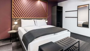 A modern hotel room with a bed, bedside table, and a large mirror. - B&B Hotel Wien St. Marx (Vienna)
