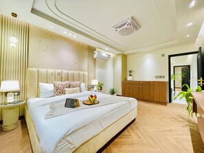 Una habitación de hotel moderna con una cama grande, mesitas de noche, un equipo de aire acondicionado y un armario de madera.