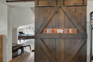 A wooden barn-style door with a sign reading "GAME ROOM" and a paw print symbol. - West End Lodge Resort Style Pool (Fredericksburg)
