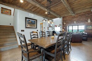 A dining area with a wooden table and chairs, a staircase, and a large window with a view.