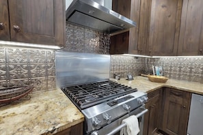 A kitchen with a stainless steel stove, wooden cabinets, and decorative backsplash. - West End Lodge Resort Style Pool (Fredericksburg)