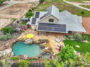 A house with a swimming pool, patio furniture, and solar panels. - West End Lodge Resort Style Pool (Fredericksburg)