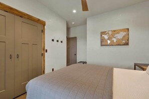 A bedroom with a large bed, a wardrobe, and a world map on the wall. - West End Lodge Resort Style Pool (Fredericksburg)