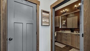 A hallway leading to a kitchen with wooden cabinets and a framed motivational quote on the wall.