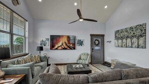 A modern living room with a grey sofa, a fireplace, and a ceiling fan. - West End Nest with Hot Tub (Fredericksburg)