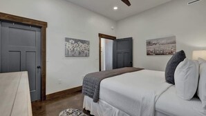 A bedroom with a bed, a ceiling fan, and two doors.