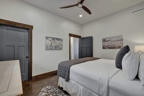 Un dormitorio con cama, ventilador de techo y dos puertas.