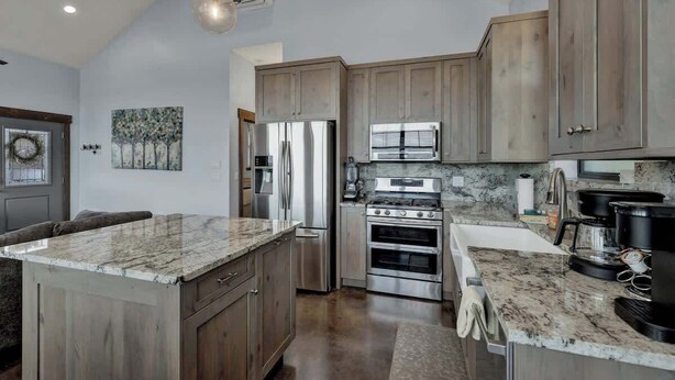 A kitchen with wooden cabinets, stainless steel appliances, and a marble countertop. - West End Nest with Hot Tub (Fredericksburg)