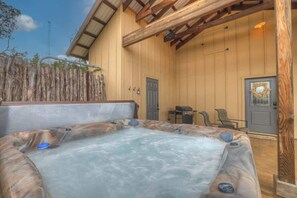 Ein Whirlpool in einer Holzhütte mit rustikalem Äußeren, einer Tür und einer kleinen Sitzecke.