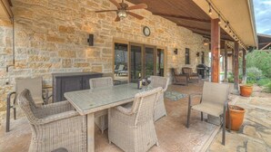 Un patio cubierto con paredes de piedra, muebles de mimbre y un ventilador de techo.