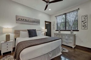 A bedroom with a bed, nightstands, a dresser, a ceiling fan, and a window with curtains. - West End Luxury Retreat-Pool/Hot-Tub & Sauna (Fredericksburg)