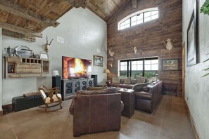 A spacious living room with a fireplace, leather sofas, and a large TV.