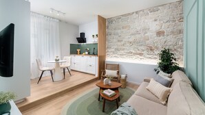 Ein modernes Wohnzimmer mit Steinswand, einer Couch, einem Couchtisch und einem Essbereich mit Tisch und Stühlen.