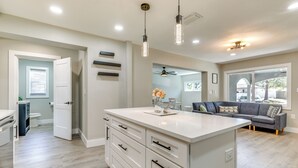 A modern kitchen with white cabinetry, a large island, pendant lighting, and a view to the dining area. - Tampa Home w/ Covered Patio: 8 Mi to Downtown! (Tampa)