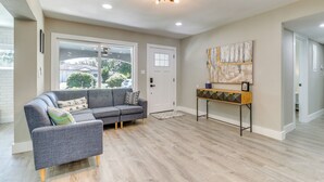 A modern living room with a gray sectional sofa, wooden flooring, and a ceiling light fixture. - Tampa Home w/ Covered Patio: 8 Mi to Downtown! (Tampa)