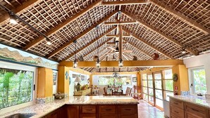 Una cocina amplia con una isla grande, armarios de madera y un techo alto con vigas a la vista.