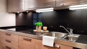 Una cocina moderna con encimera negra, pileta de acero inoxidable y muebles de madera.