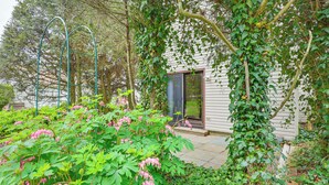 A garden with a pergola, a house with a sliding glass door, and lush greenery. - Quaint Bristol Townhome ~ 14 Mi to West Hartford! (Bristol)