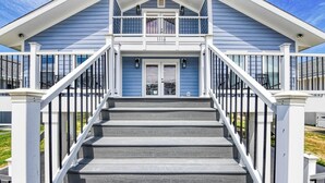 Une maison à deux étages avec un porche à l’avant et un escalier menant à l’entrée.