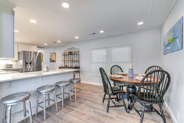 A modern kitchen with a central island, bar stools, and a dining table with chairs. - Private Beach,gated Parking,showers Bathrooms (Murrells Inlet)