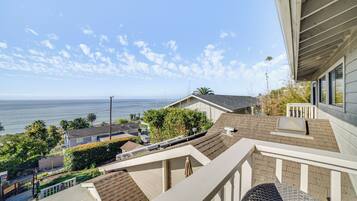 Enjoy ocean views from the house's balcony, surrounded by lush greenery and a well-manicured lawn.