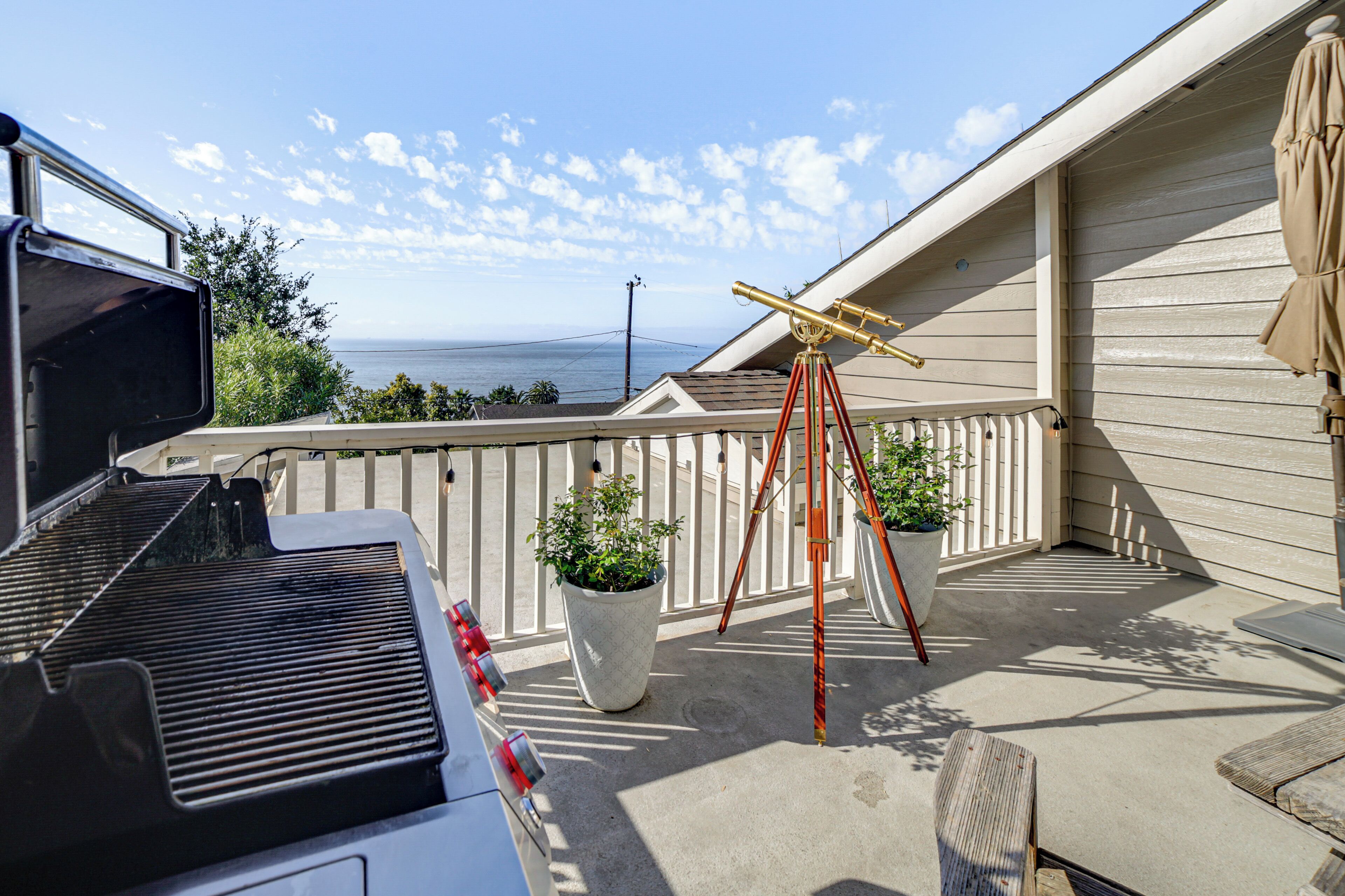 A patio with a grill, potted plants, and a telescope.