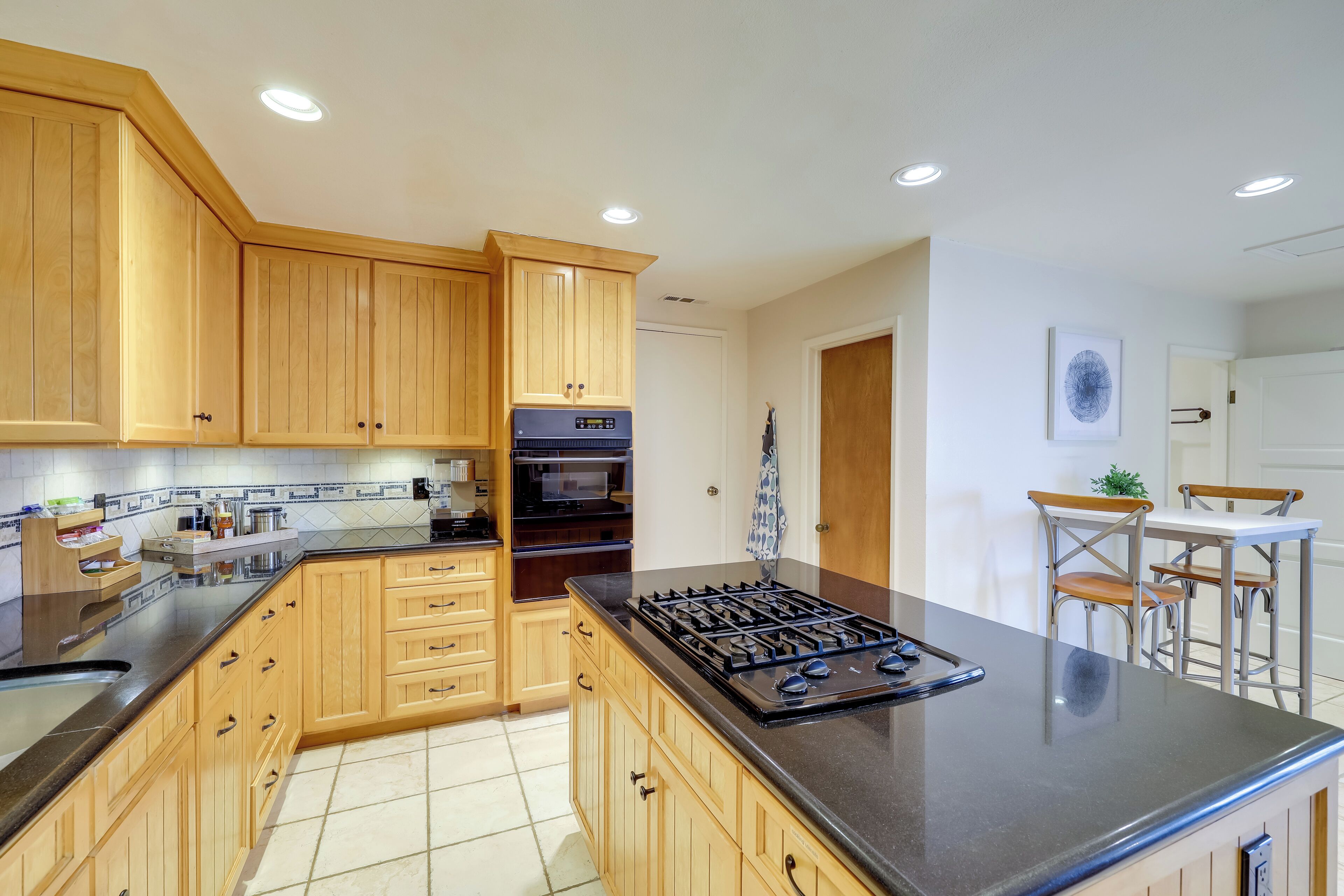 A kitchen with wooden cabinets, a gas stove, and a dining area with a table and chairs.