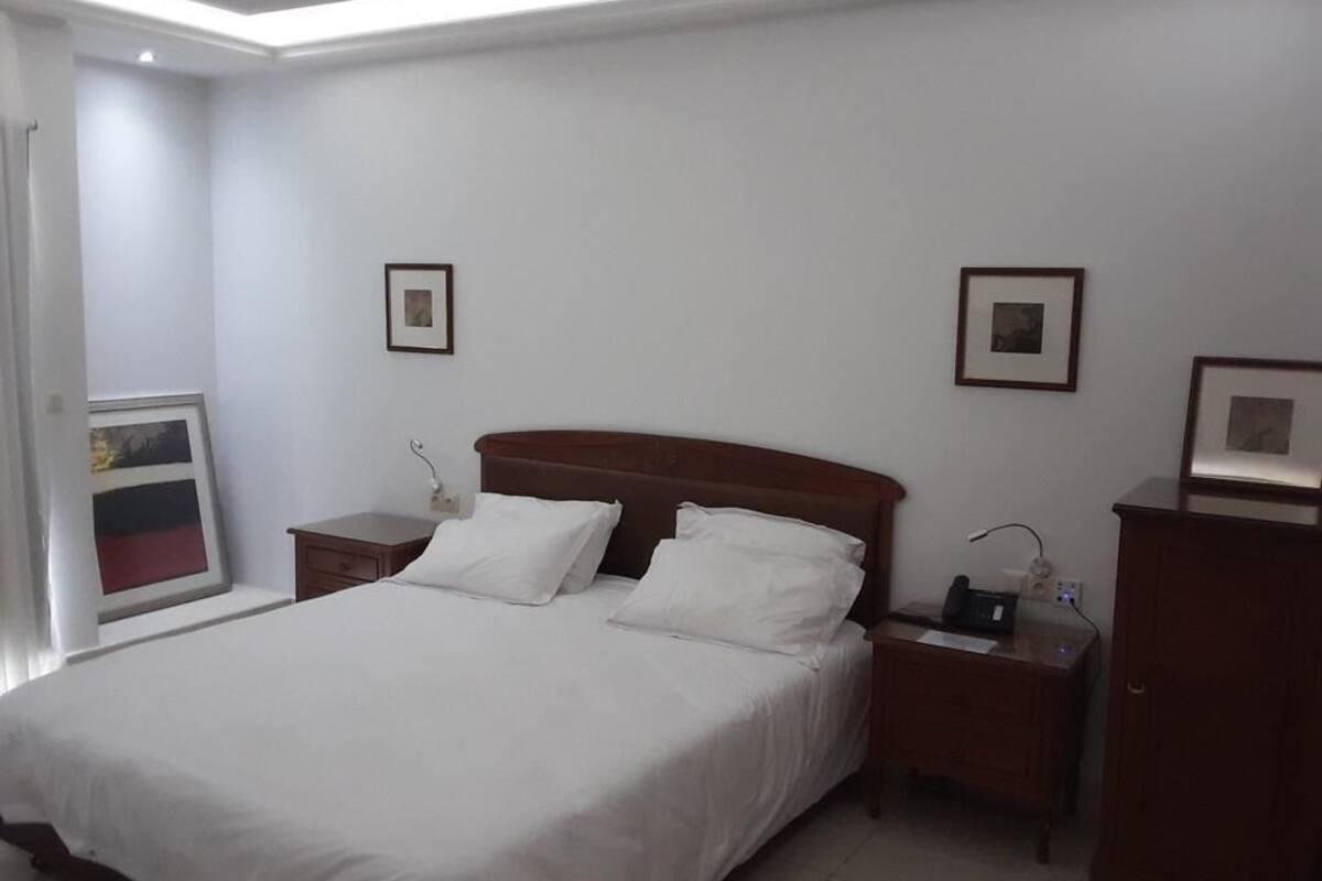 A neatly arranged bedroom with a large bed, two bedside tables, and a wardrobe.