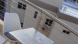 A balcony with a metal railing, a small table, and two white chairs. - Résidence Mad 75 (Dakar)