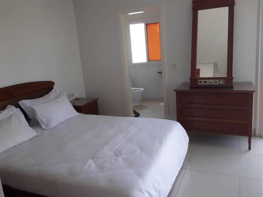 Une chambre à coucher avec un lit, une commode et un miroir.