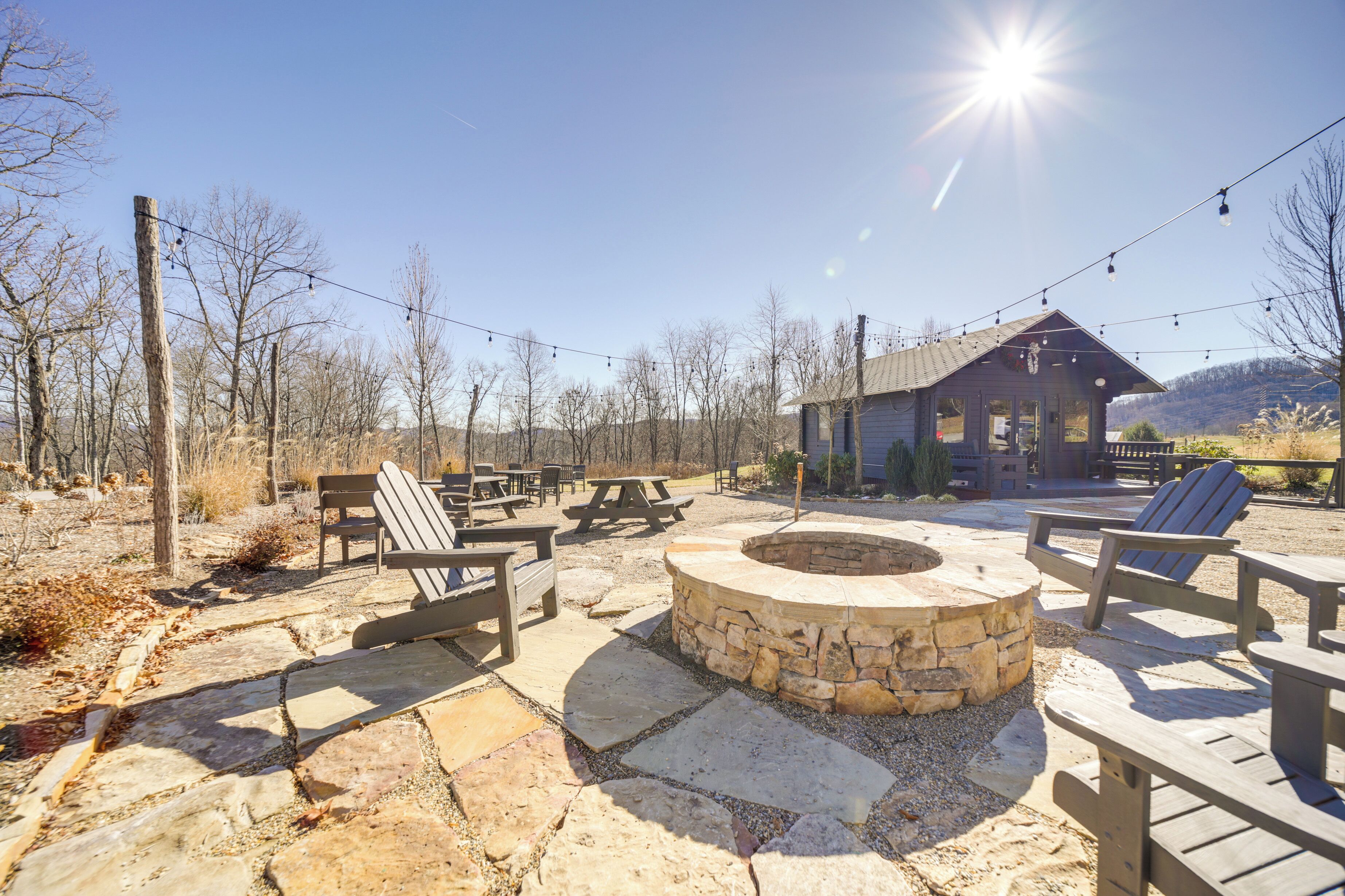 An outdoor patio with stone seating, a fire pit, and a wooden building in the background.