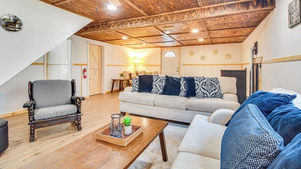 A spacious living room with a high ceiling, a wooden ceiling fan, a sofa, a chair, and a coffee table with decorative items. - Charming Maine Retreat Near Skiing & ATV Park! (Dixfield)