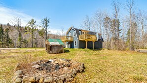 A two-story house with a wooden deck and a small shed in a wooded area. - Charming Maine Retreat Near Skiing & ATV Park! (Dixfield)