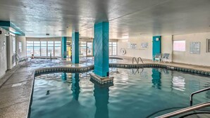 An indoor swimming pool with clear water, blue pillars, and a tiled edge. - Walk to Beach: North Myrtle Beach Resort Apt! (North Myrtle Beach)