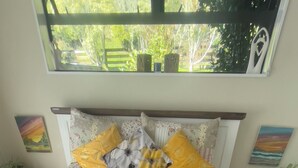 A neatly made bed with floral bedding, a yellow throw blanket, and a white towel. - Mel’s Retreat - Private Room & Ensuite (Te Kuiti)