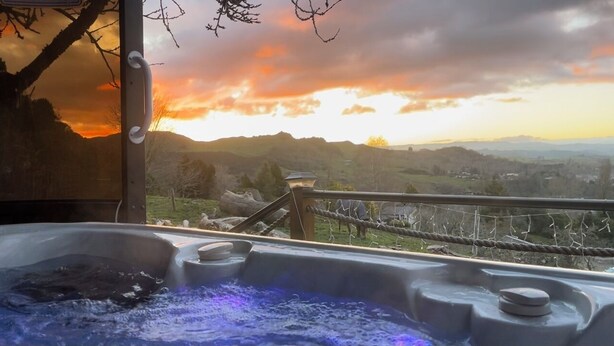 A hot tub with a view of a sunset over a mountainous landscape. - Mel’s Retreat - Private Room & Ensuite (Te Kuiti)