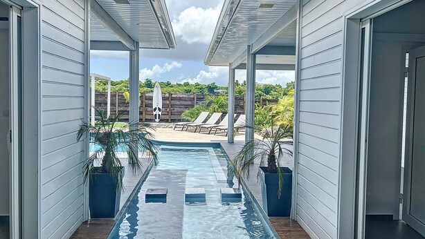 A covered outdoor swimming pool with lounge chairs and a wooden deck. - Nakolodge 4 chambres - piscine / balneo / jardin privatifs  (Sainte-Anne)