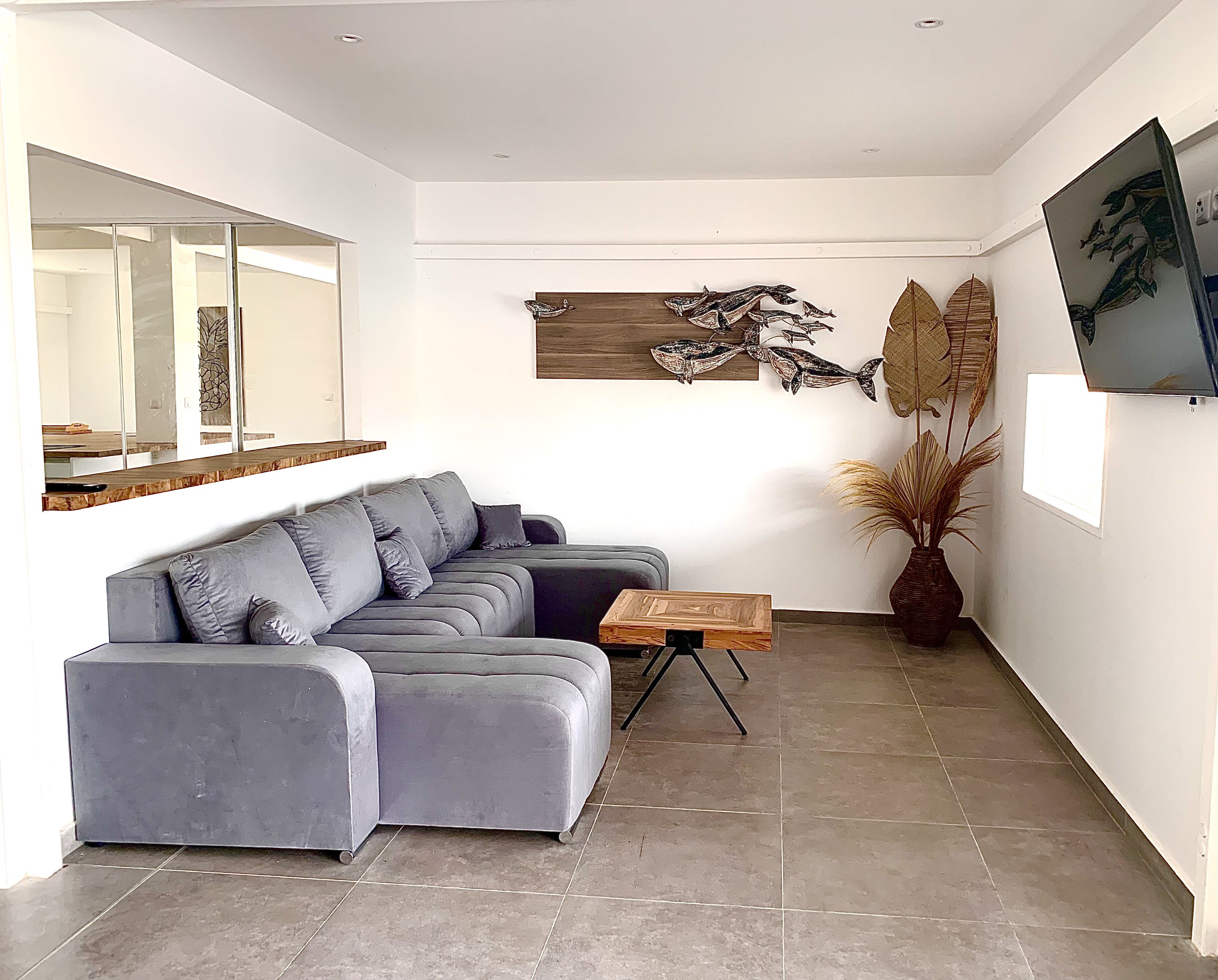 A modern living room with a grey sectional sofa, a wooden coffee table, and a large mirror.