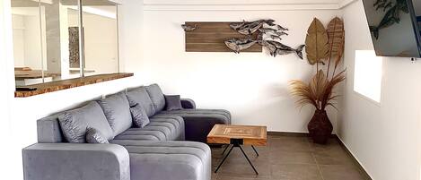 A modern living room with a grey sectional sofa, a wooden coffee table, and a large mirror.