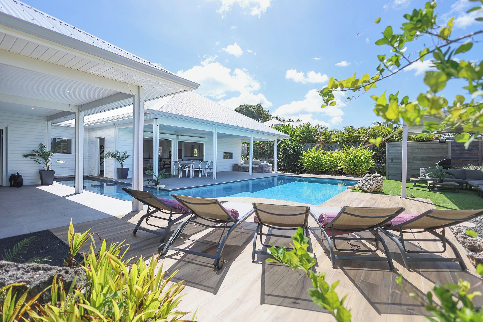 A modern house with a swimming pool, outdoor seating, and a covered patio area.
