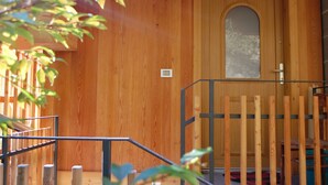 Un intérieur en bois avec une porte, une petite fenêtre et une rambarde en métal.