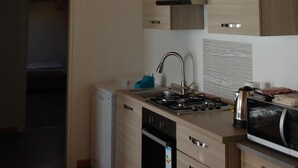Une cuisine moderne avec des poutres en bois, une cuisinière intégrée et un lave-vaisselle compact.