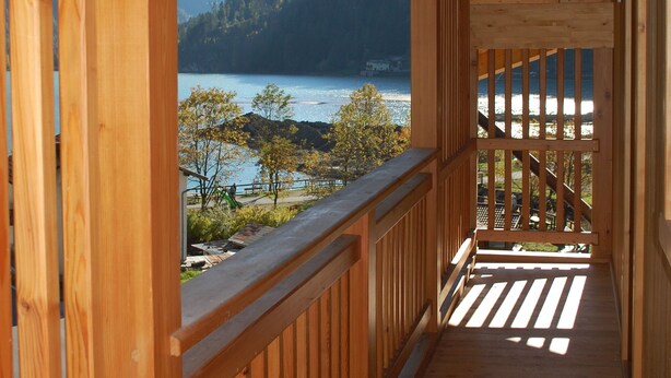Un balcon en bois offrant une vue sur un lac et des montagnes.